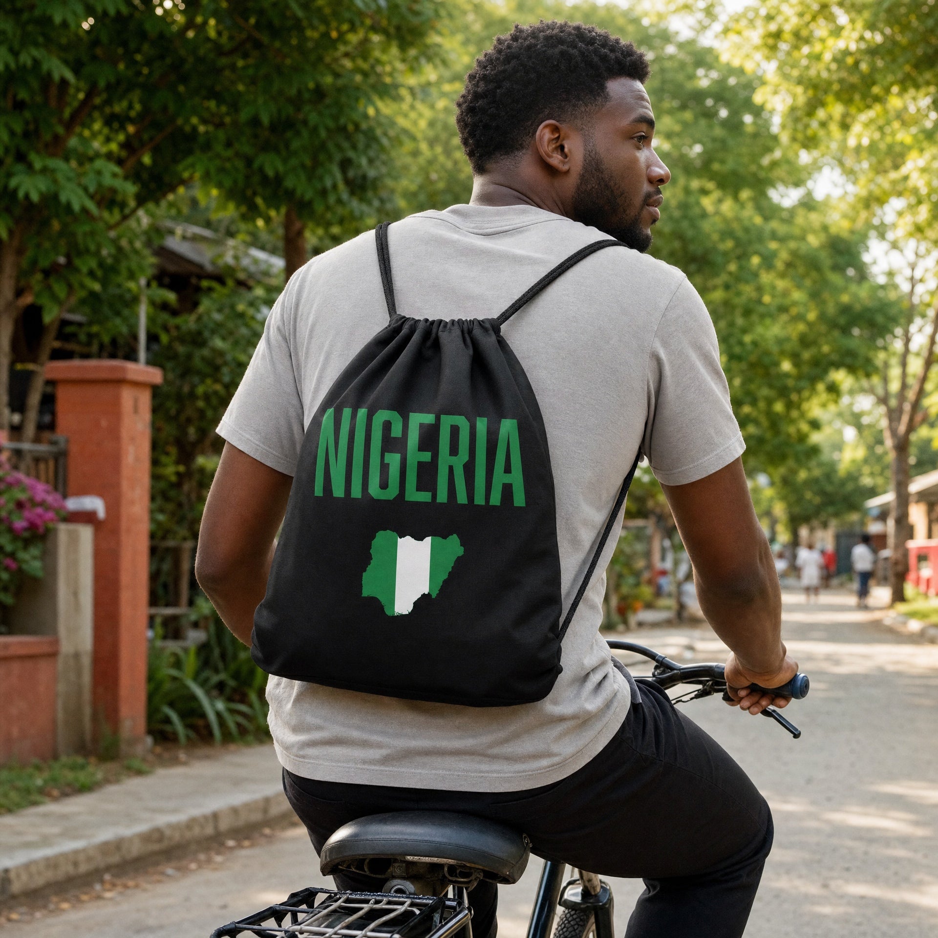 Man wearing the black Nigeria Classic drawstring bag with green Nigeria map graphic while cycling.