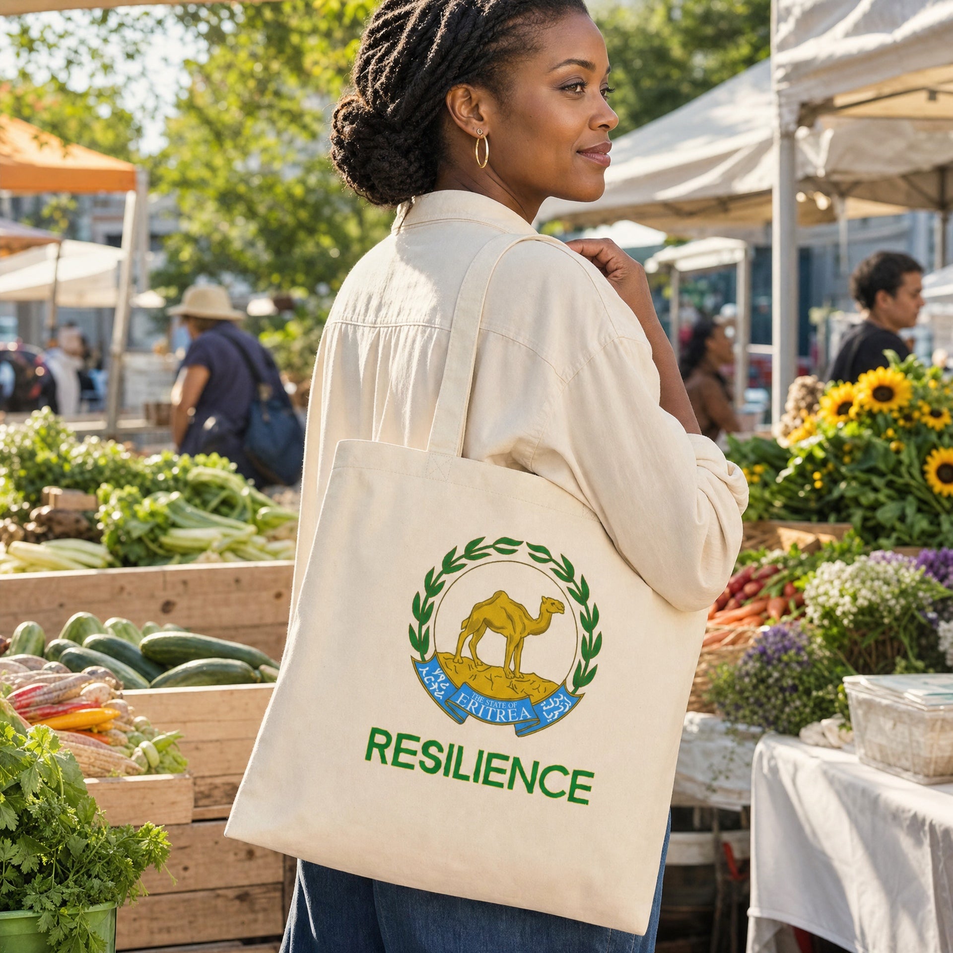 Woman carrying the natural-canvas Eritrean Resilience tote bag with green crest and gold lion at a farmers market.